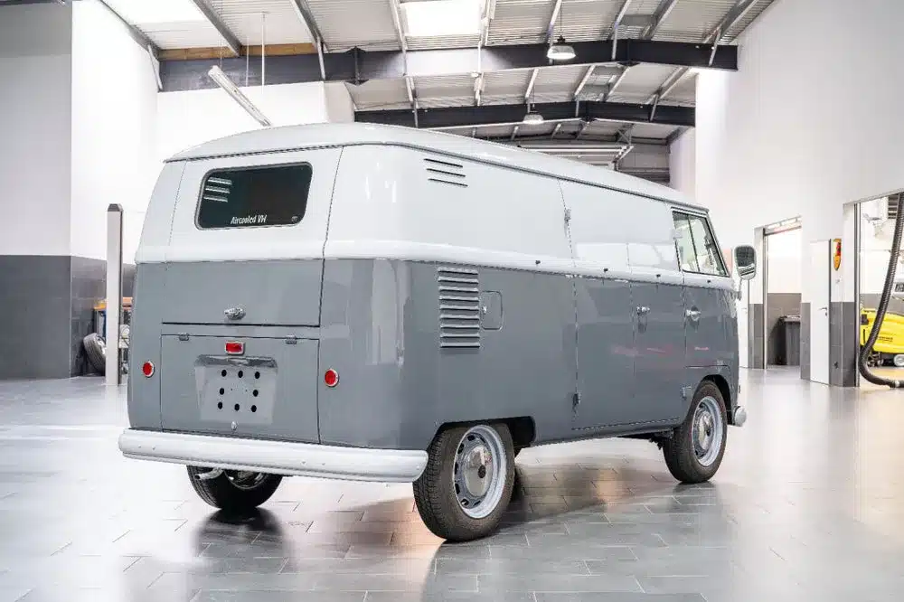 Restaurierter VW T1 Kastenwagen von 1956 in grauer Lackierung, Rückansicht in moderner Halle.
