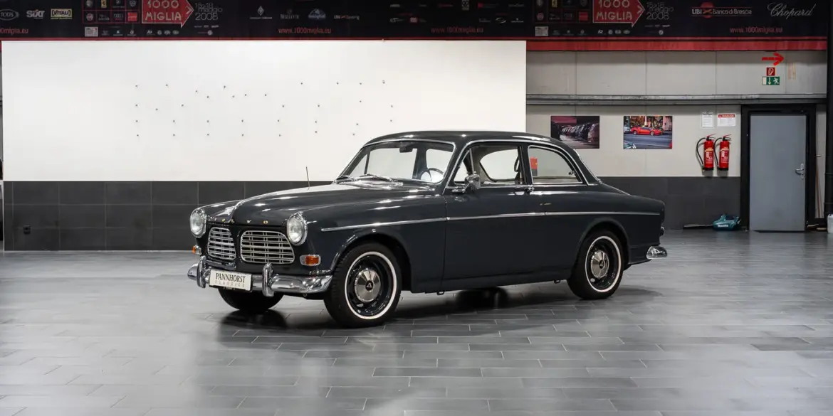 Restauriertes Volvo Amazon Coupé, Baujahr 1964, in dunkler Farbe, Seitenansicht in einer modernen Halle.