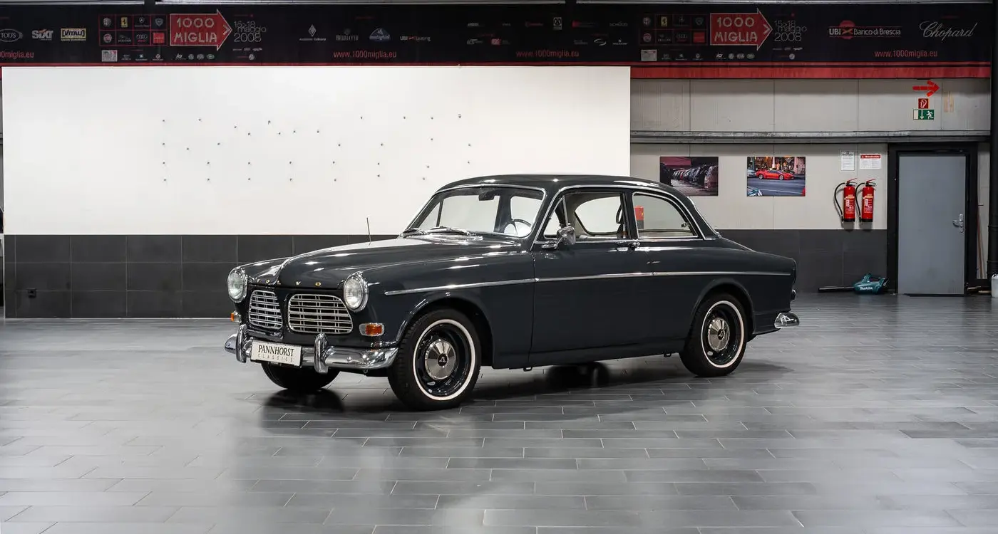 Restauriertes Volvo Amazon Coupé, Baujahr 1964, in dunkler Farbe, Seitenansicht in einer modernen Halle.