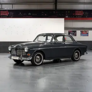 Restauriertes Volvo Amazon Coupé, Baujahr 1964, in dunkler Farbe, Seitenansicht in einer modernen Halle.