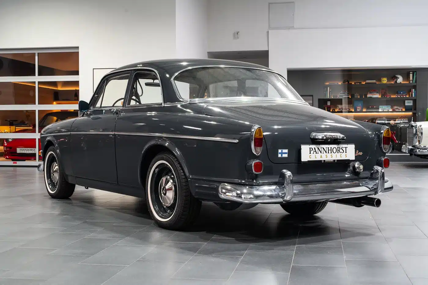 Volvo Amazon Coupé von 1964, dunkel lackiert, fotografiert von hinten in einer modernen Ausstellungshalle