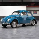Blauer VW Käfer 1200 aus dem Jahr 1964 im originalen Zustand in einer Ausstellungshalle.