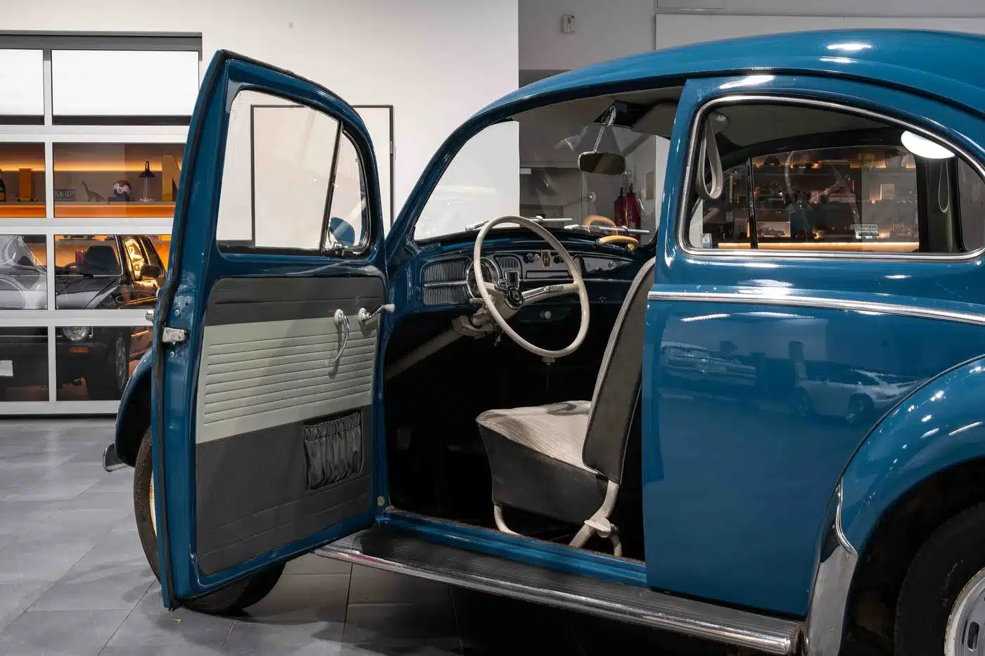 Blick in den original erhaltenen Innenraum eines blauen VW Käfer 1200 von 1964 mit geöffneter Fahrertür