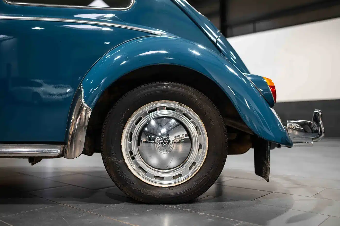 Detailaufnahme des hinteren Radkastens eines VW Käfer 1200 von 1964 mit charakteristischer originaler Felge und Chromstoßstange.