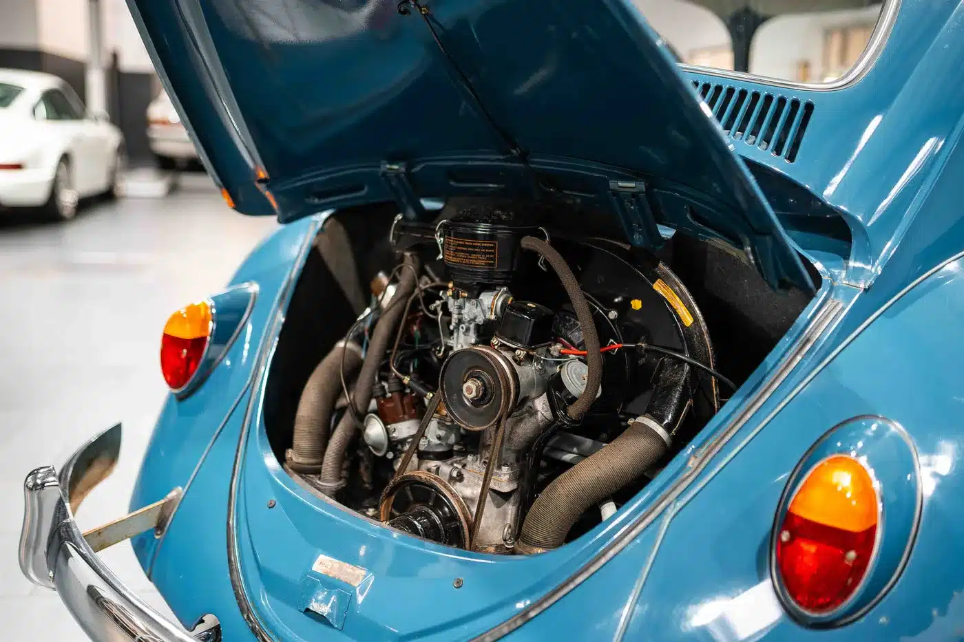 Offener Motorraum eines blauen VW Käfer 1200 von 1964 mit sichtbarem 1,2-Liter-Boxermotor.