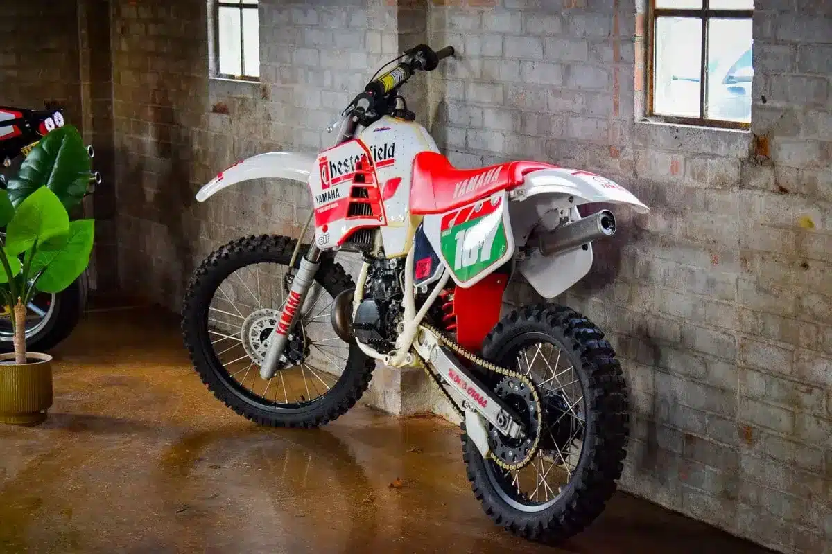 Yamaha YZ250 Modelljahr 1987 in weiß-roter Chesterfield-Lackierung, abgestellt an einer Backsteinwand.