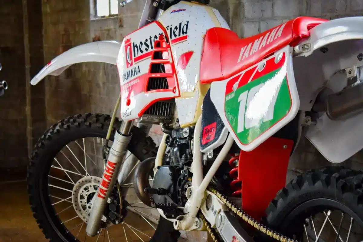 Nahaufnahme einer Yamaha YZ250 von 1987 mit Chesterfield-Grafik, betont die authentische Patina und technische Details des klassischen Zweitakt-Motorrads.