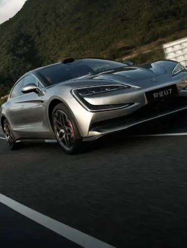 Silberner YangWang U7 fährt auf einer kurvigen Bergstraße, im Vordergrund die markante Front des Flaggschiffs, umgeben von grüner Hügellandschaft.