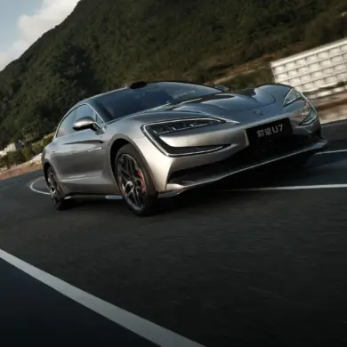 Silberner YangWang U7 fährt auf einer kurvigen Bergstraße, im Vordergrund die markante Front des Flaggschiffs, umgeben von grüner Hügellandschaft.