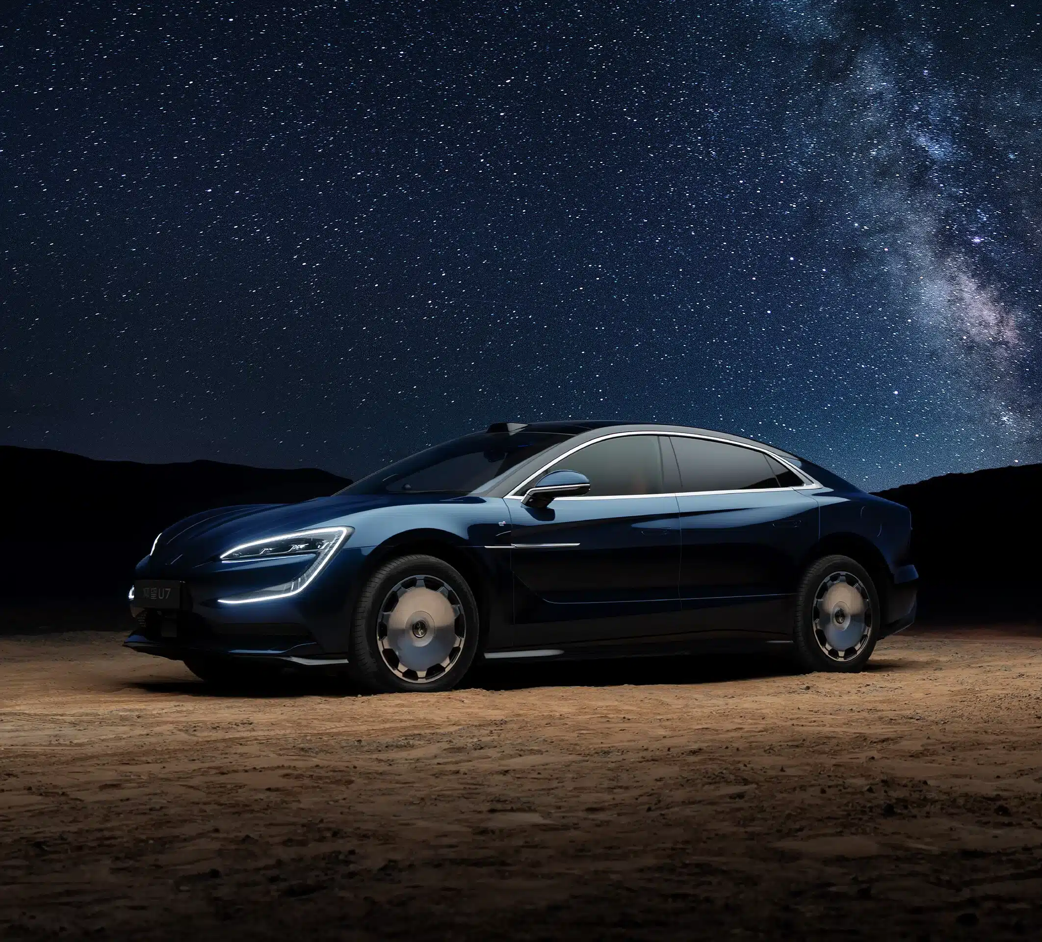 YangWang U7 in dunkler Lackierung auf sandigem Boden vor klarem Sternenhimmel.