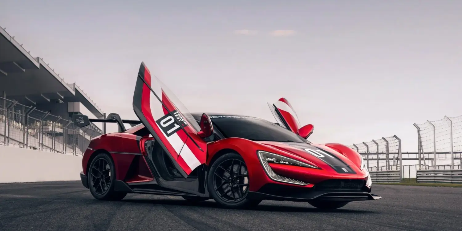 Yangwang U9 Xtreme mit geöffneten Flügeltüren auf einer Rennstrecke, seitliche Ansicht.