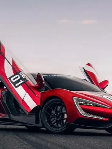 Yangwang U9 Xtreme mit geöffneten Flügeltüren auf einer Rennstrecke, seitliche Ansicht.