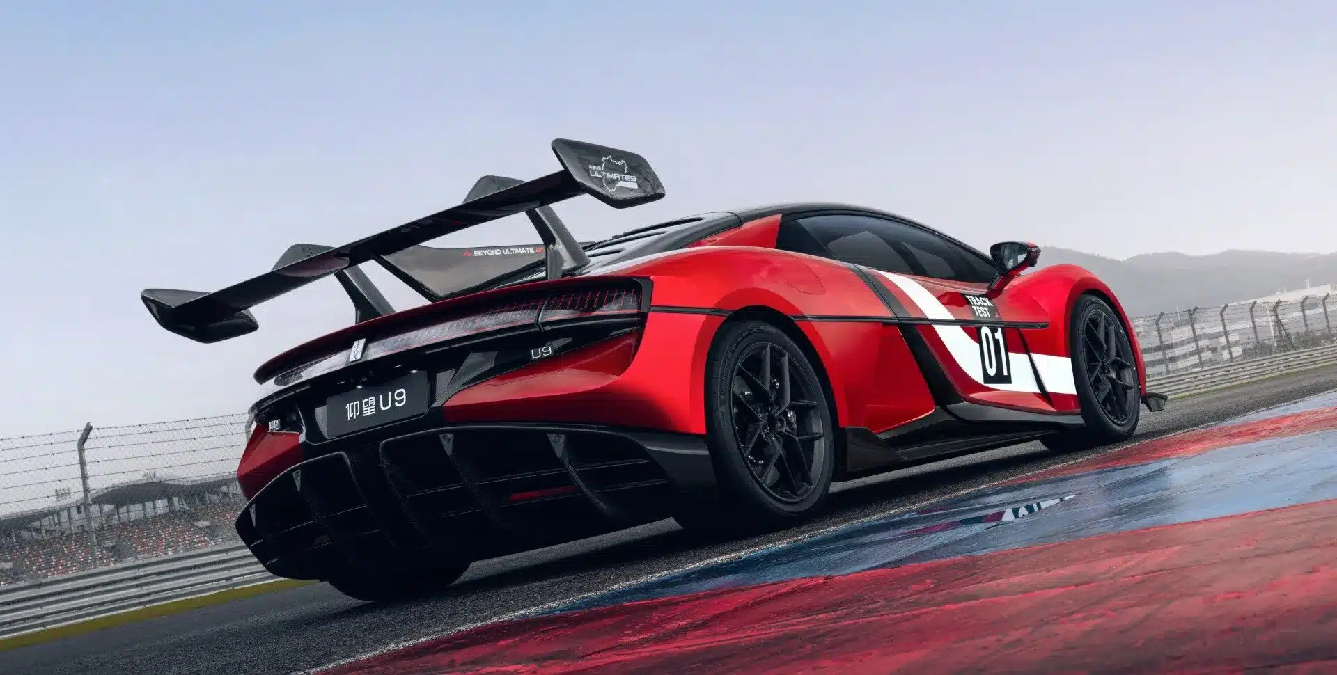 Heckansicht des roten Yangwang U9 Xtreme mit großem Heckflügel auf einer Rennstrecke