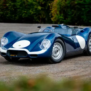 Lister-Jaguar Knobbly Continuation in Blau auf Schotter, Rennsport-Silhouette von vorn schräg fotografiert.