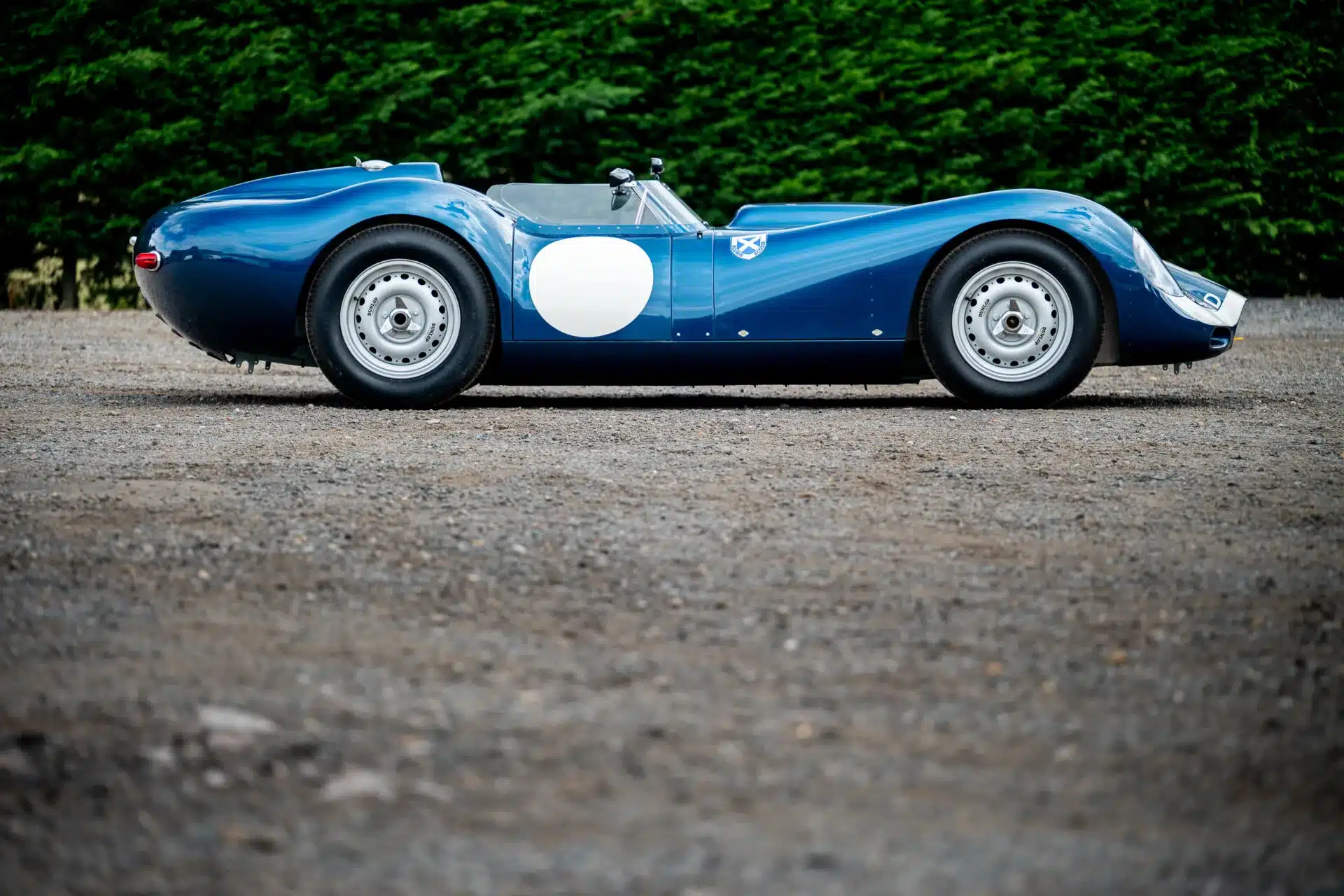 Lister-Jaguar Knobbly Continuation, Seitenansicht in Ecurie-Ecosse-Blau, auf Schotter stehend.