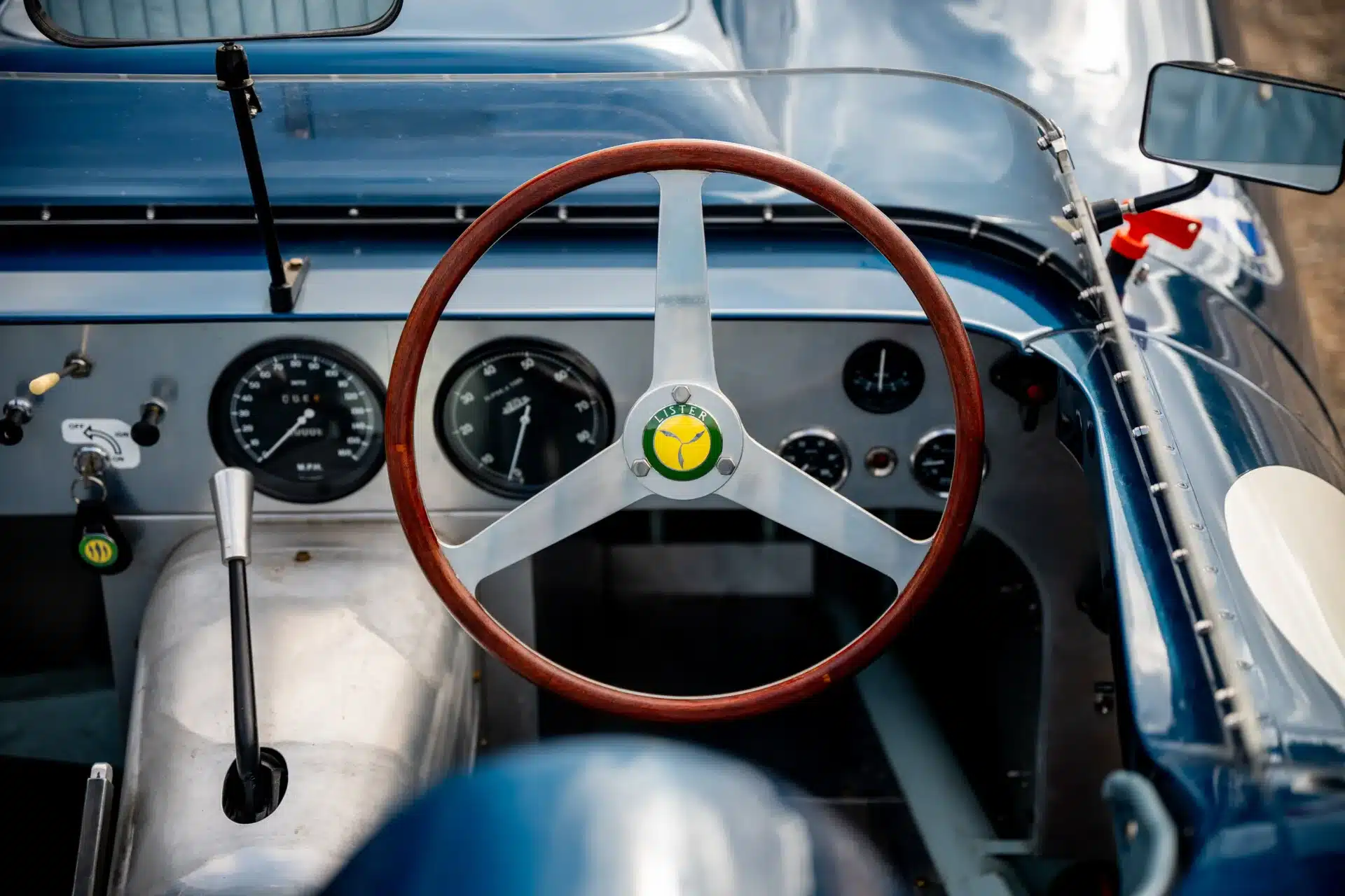 Innenansicht des Cockpits eines Lister-Jaguar Knobbly Continuation mit Holzlenkrad und klassischen Rundinstrumenten.