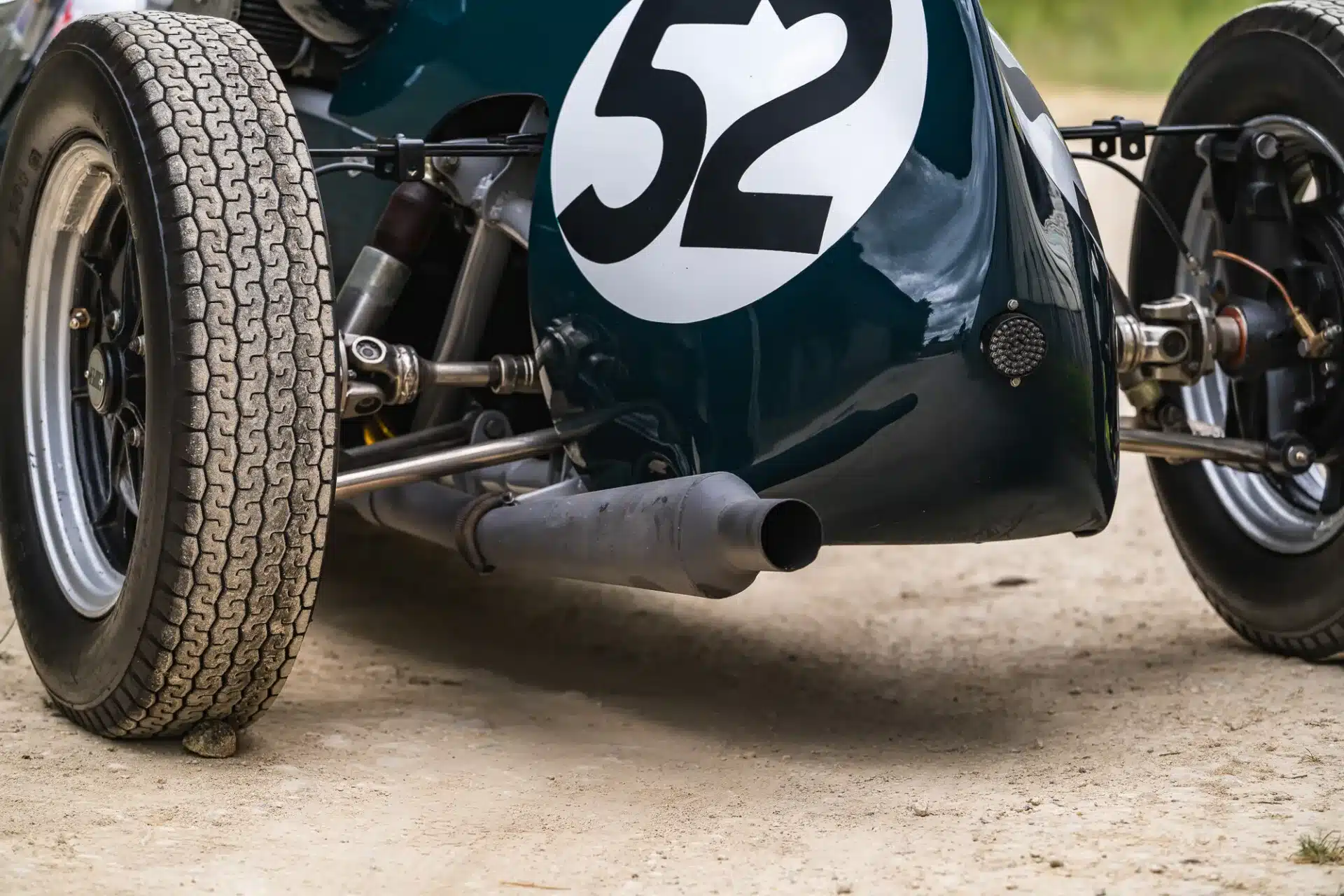 Detailansicht des hinteren Bereichs eines Cooper BMC T52 mit Startnummer 52, Auspuff und Rennreifen.