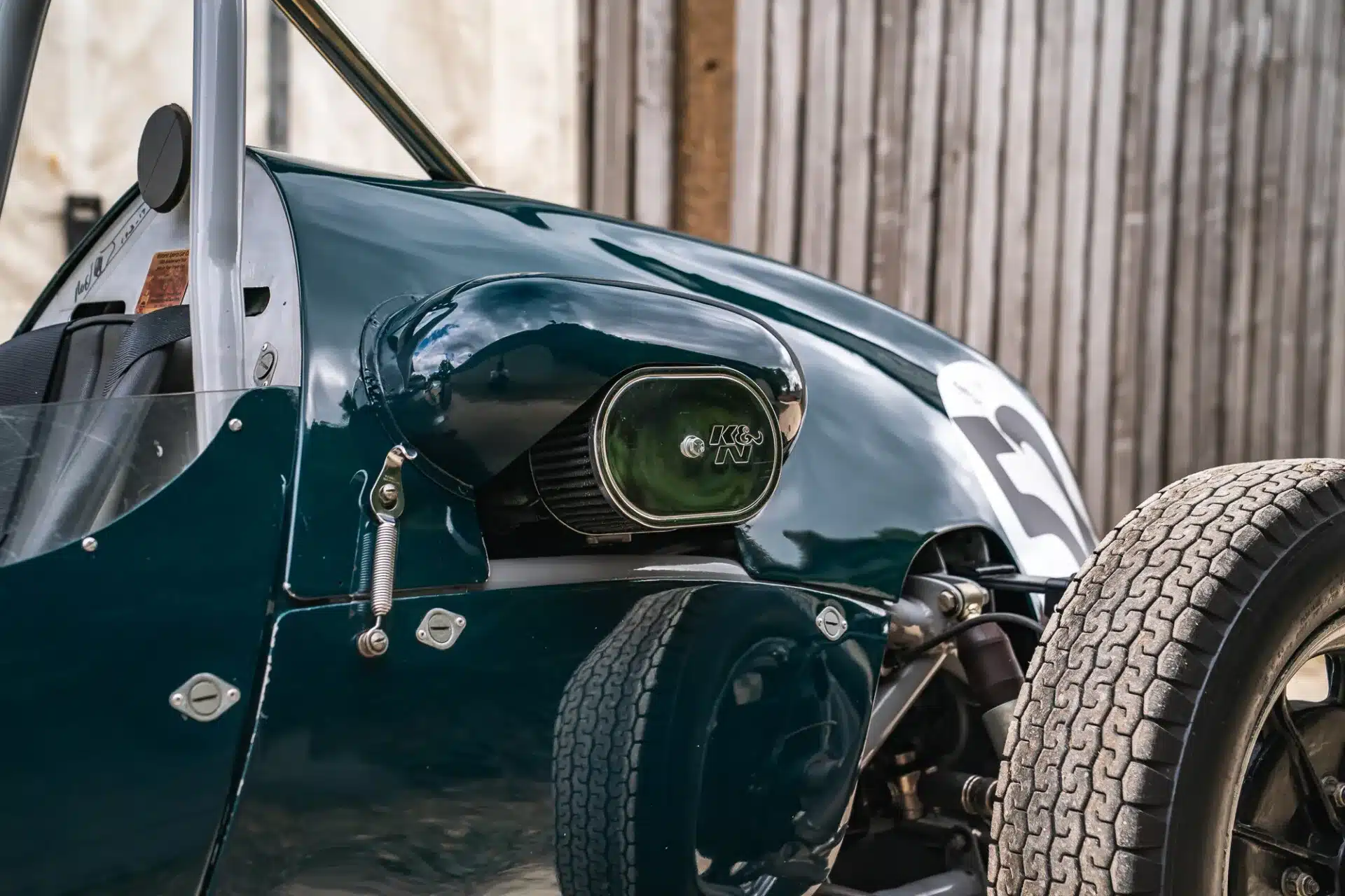 Detailaufnahme des Cooper BMC T52 von 1960, dunkelgrün lackiert, mit K&N Luftfilter, Rennsportreifen und Startnummer.