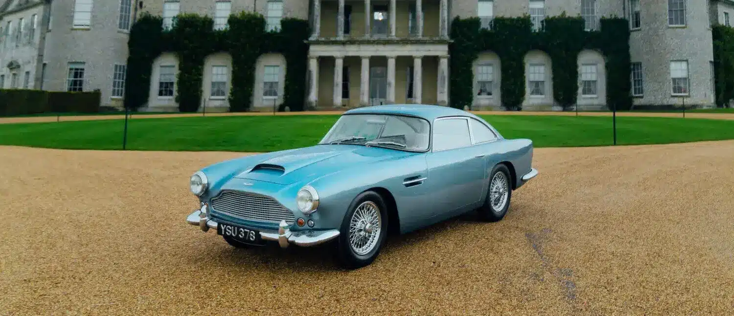 Aston Martin DB4 Series III Vantage 1961 in Caribbean Pearl, geparkt vor einem Herrensitz.