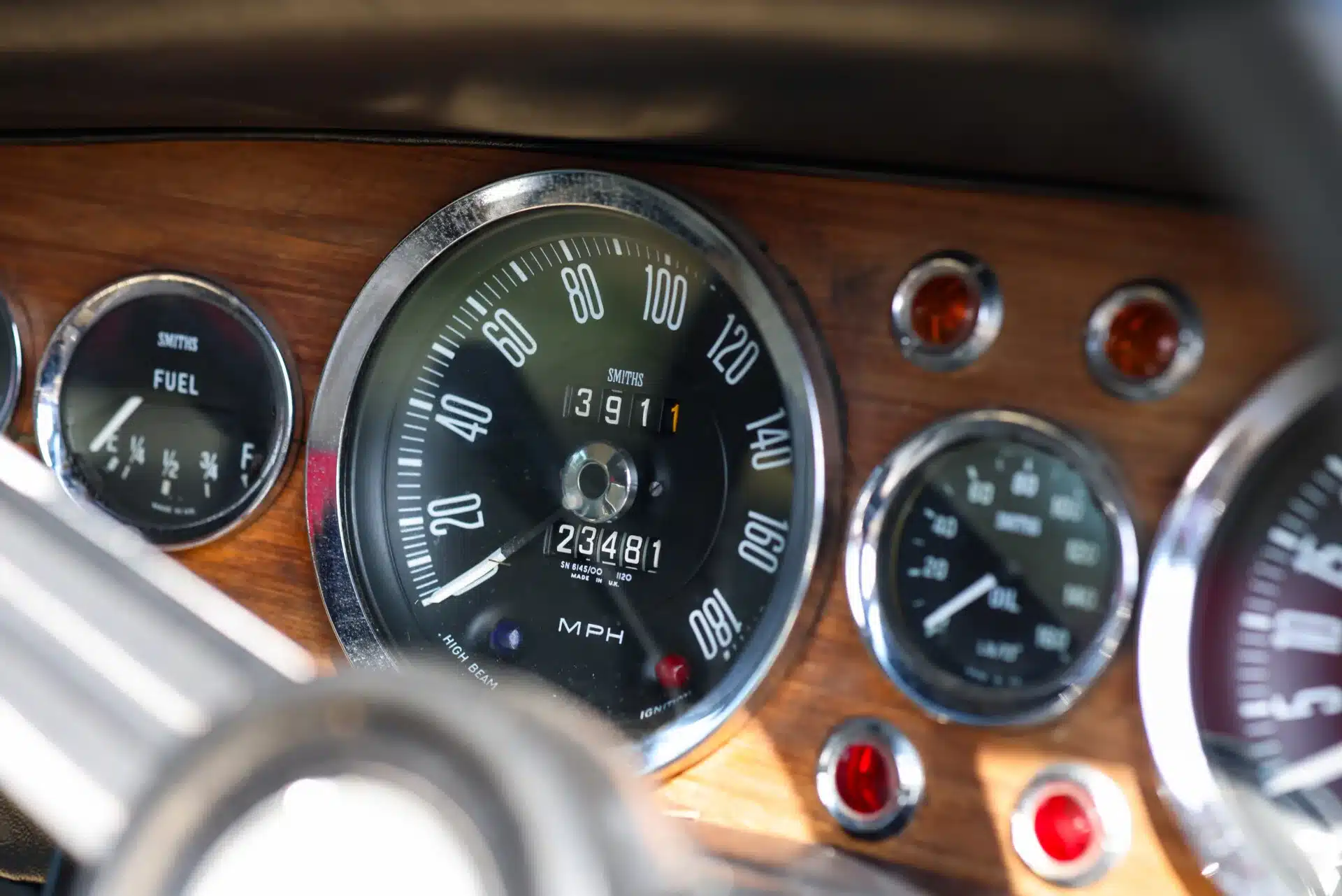 Close-up der klassischen Rundinstrumente im Cockpit eines 1969 Aston Martin DBS, unter anderem Geschwindigkeitsanzeige, Tankanzeige und Öldruckmesser vor Holzdekor.