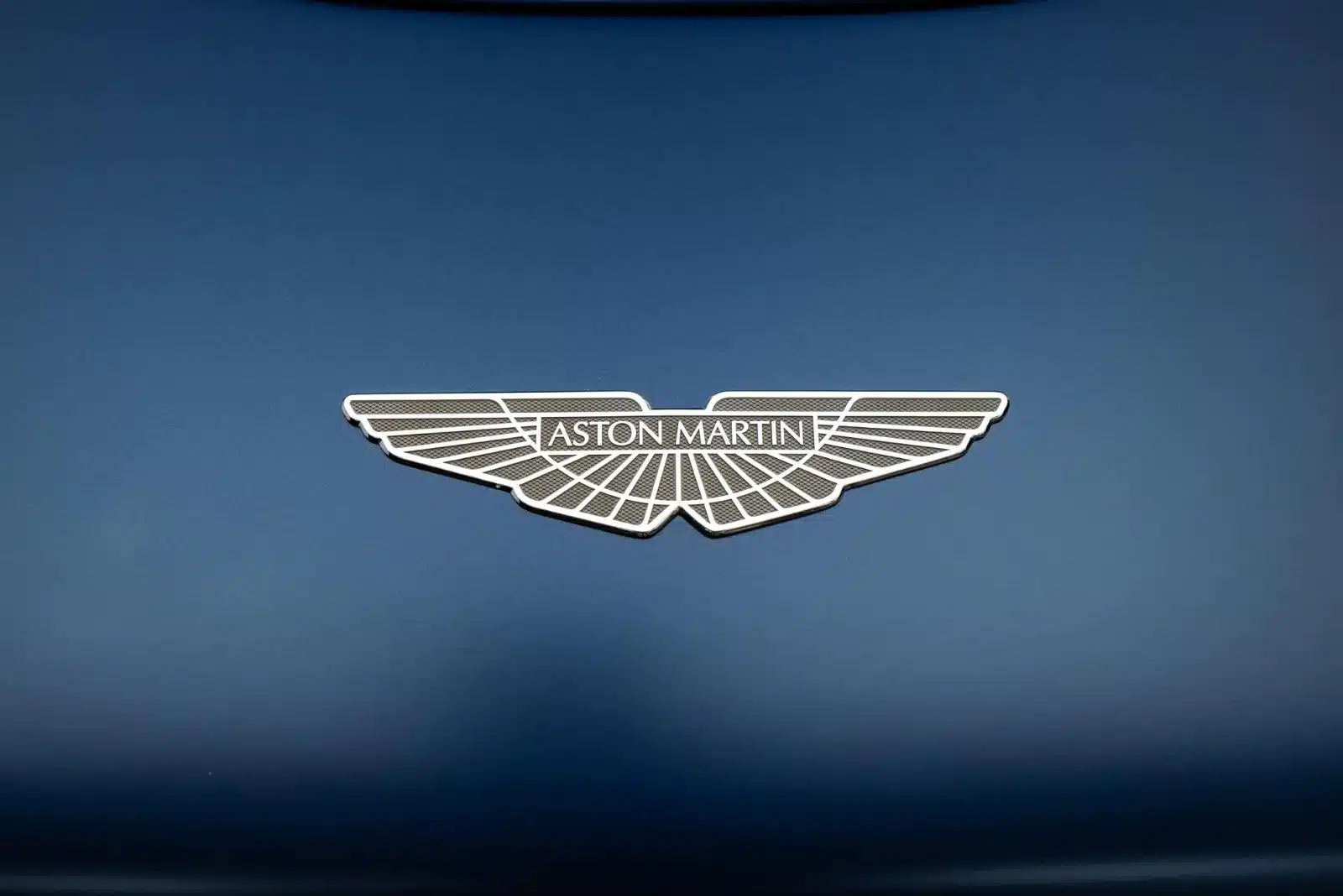 Aston Martin Emblem auf blauem Hintergrund