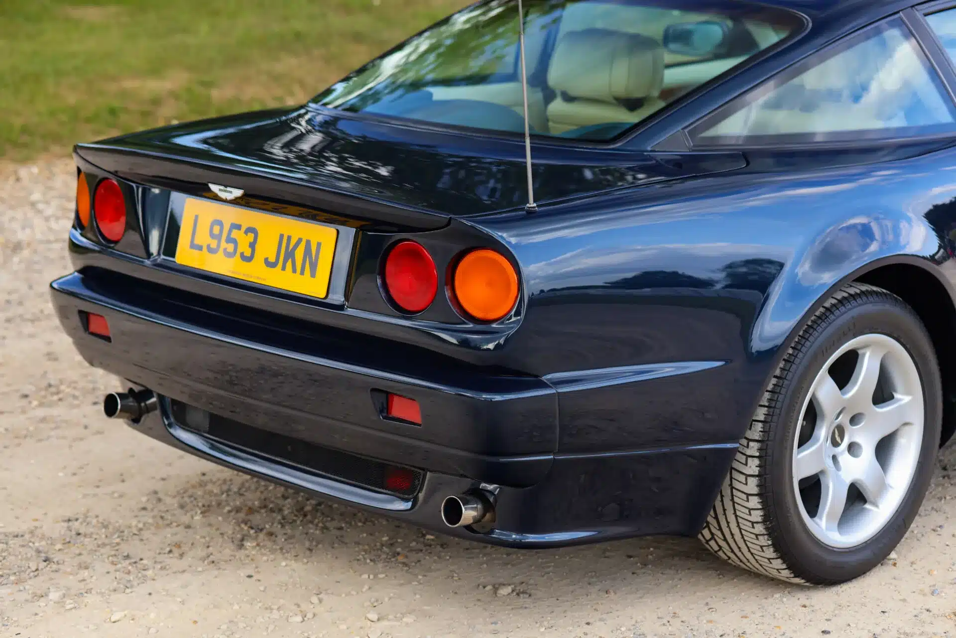 Aston Martin Vantage V550 von 1994 in Royal Blue metallic aus der Heckperspektive mit breiten Radläufen und Doppelauspuff.