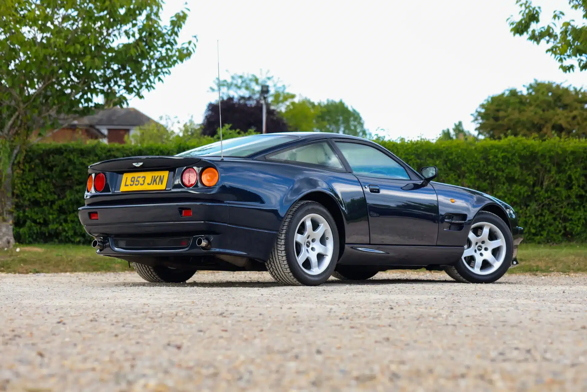 Aston Martin Vantage V550, Baujahr 1994, in Royal Blue Metallic, Rückansicht auf einem Kiesplatz.