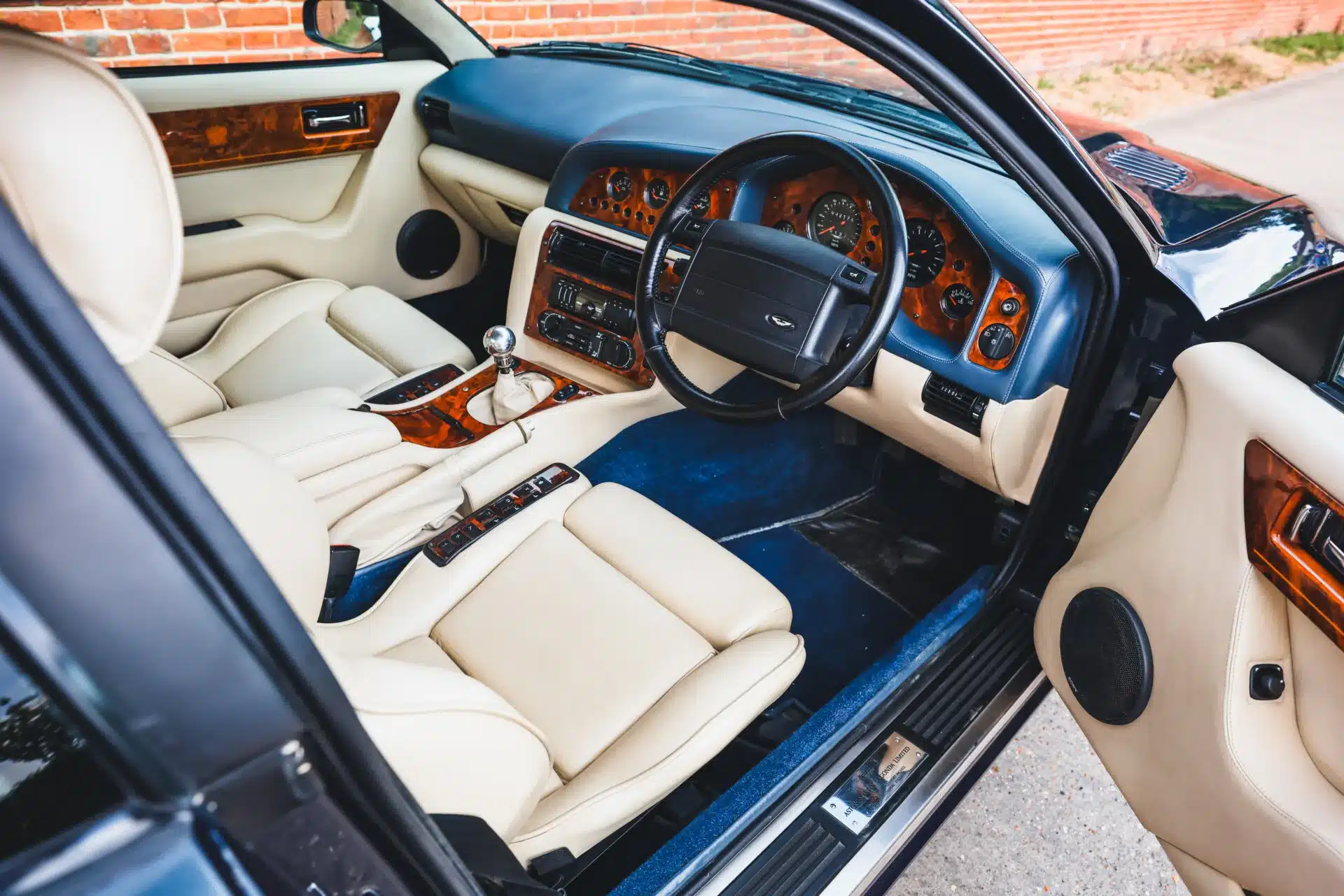 Innenansicht eines Aston Martin Vantage V550 mit cremefarbenem Leder und Wurzelholzfurnier.