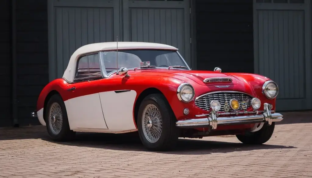 Austin-Healey 3000 MK1 BT7, Baujahr 1959, mit roter Lackierung und weißem Werks-Hardtop, von schräg vorne fotografiert.