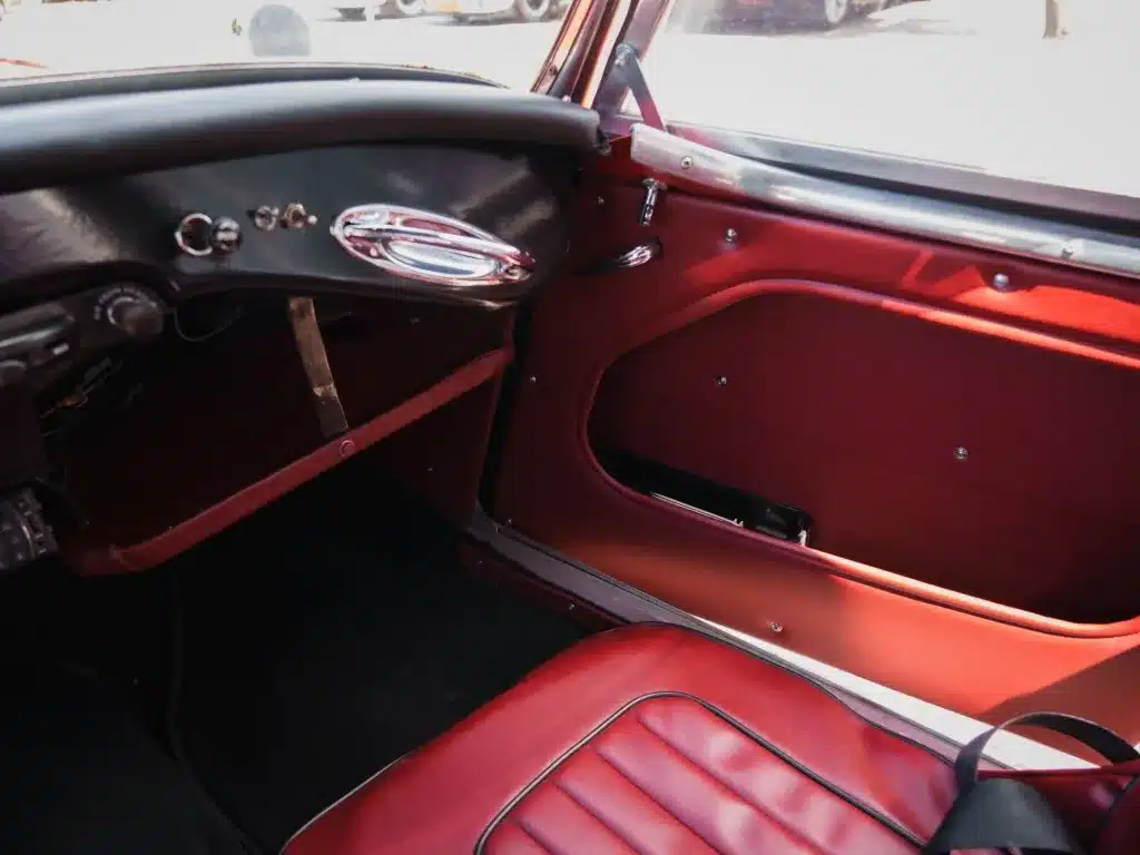 Innenraum eines Austin-Healey 3000 MK1 BT7 von 1959 mit roter Lederausstattung und klassischen Elementen.