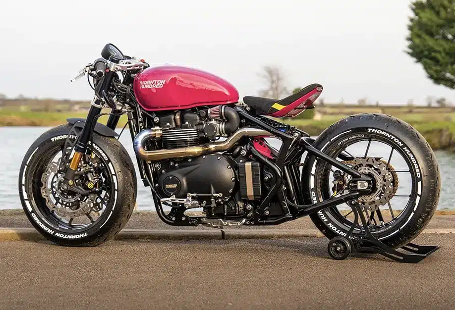 Seitliche Ansicht einer maßgeschneiderten Bespoke Bobber mit rotem Tank, speziellem Auspuff und Custom-Elementen