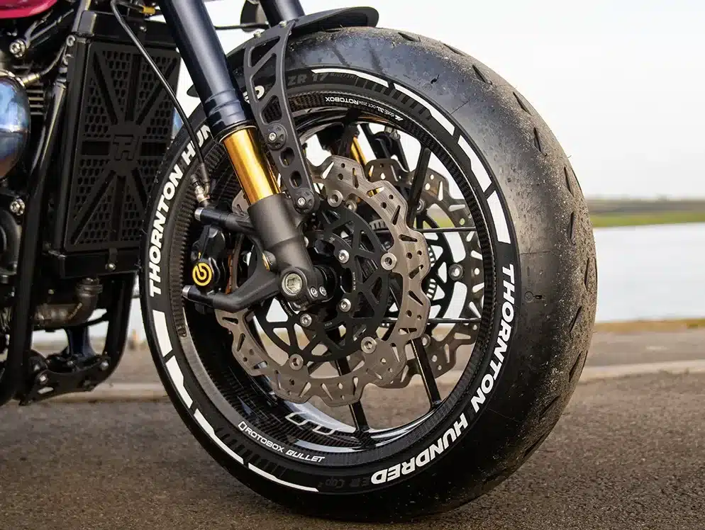 Vorderrad einer Bespoke Bobber mit leichter Carbonfelge und sportlicher Bremsscheibe auf Asphalt.
