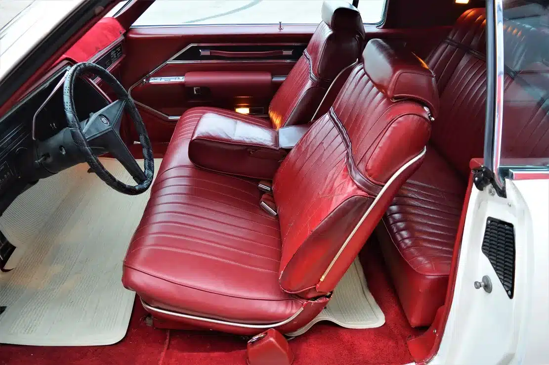 Roter Leder-Innenraum eines weißen Cadillac Eldorado Coupe aus den 1960er Jahren, mit geöffneter Fahrertür.