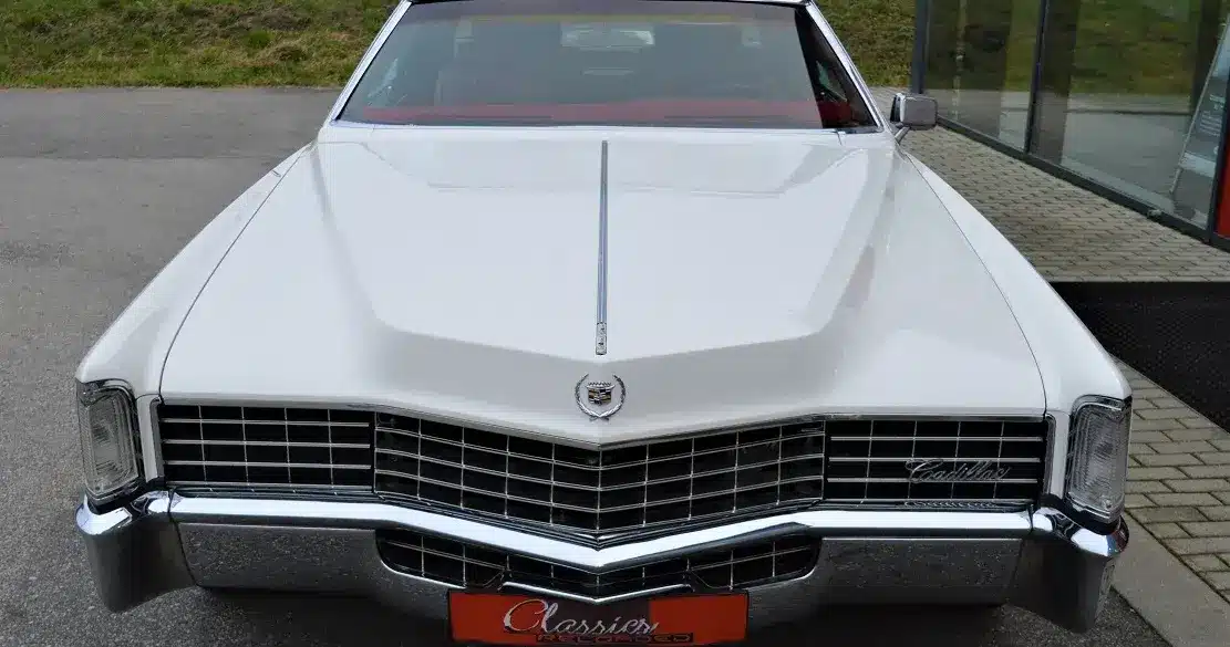 Frontansicht eines weißen Cadillac Eldorado Coupé Baujahr 1969 mit schwarzem Vinyl-Dach und markanter Kühlergrill-Gestaltung.