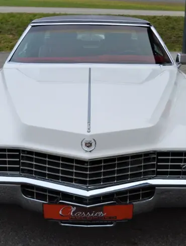 Frontansicht eines weißen Cadillac Eldorado Coupé Baujahr 1969 mit schwarzem Vinyl-Dach und markanter Kühlergrill-Gestaltung.