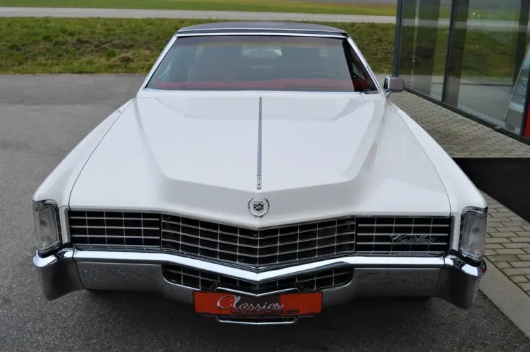 Frontansicht eines weißen Cadillac Eldorado Coupé Baujahr 1969 mit schwarzem Vinyl-Dach und markanter Kühlergrill-Gestaltung.