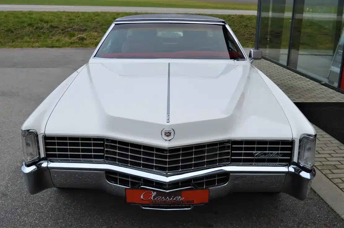 Frontansicht eines weißen Cadillac Eldorado Coupé Baujahr 1969 mit schwarzem Vinyl-Dach und markanter Kühlergrill-Gestaltung.