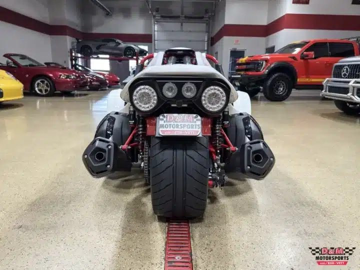 Heckansicht eines weißen Campagna T‑Rex RR 2025 in einer modernen Fahrzeughalle mit sichtbarem Überrollkäfig, breiter Hinterachse und aufwändigem Fahrwerk.