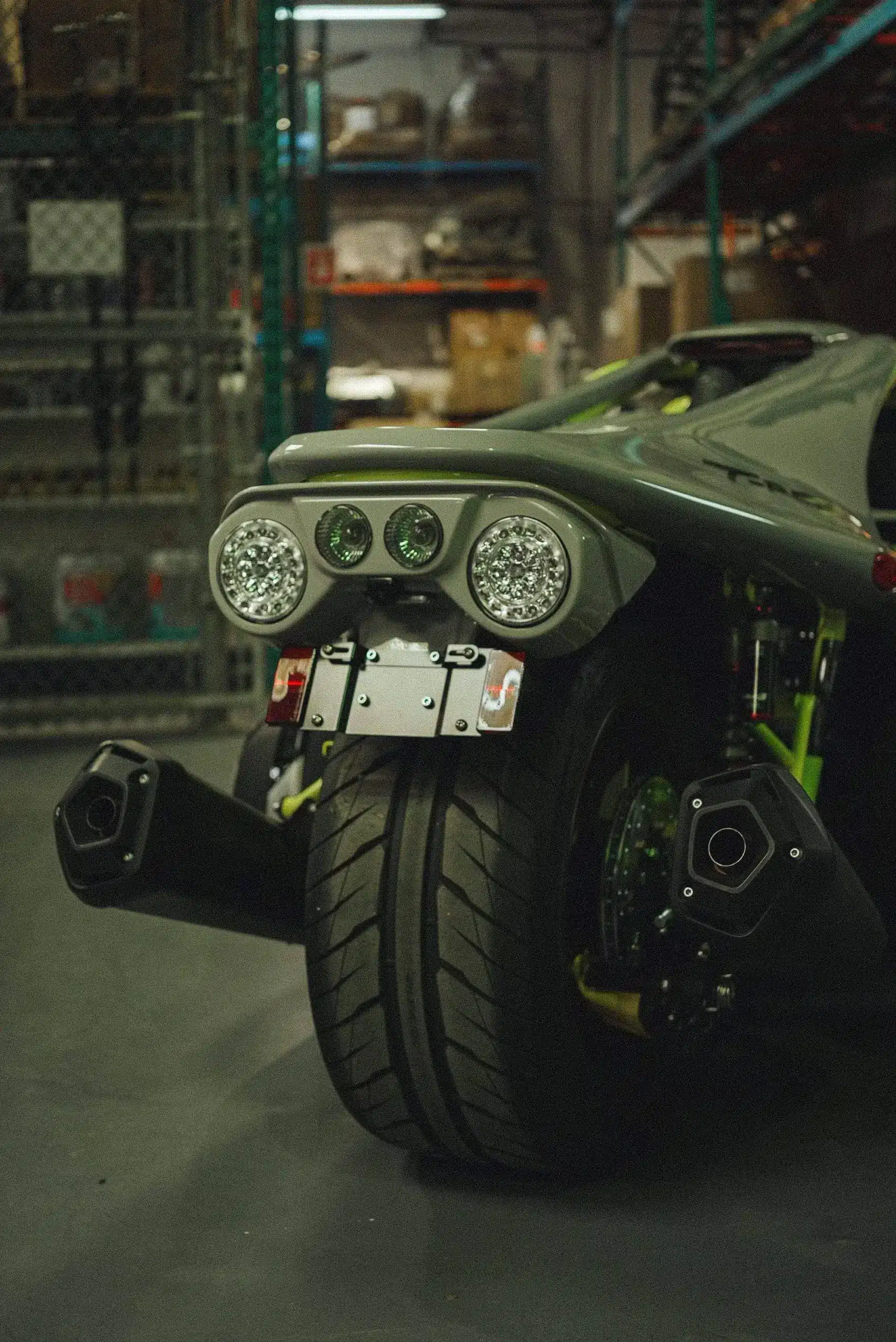 Heck des Campagna T-REX RR 2026 mit großem Reifen, LED-Leuchten und zwei Auspuffrohren, fotografiert in einer Halle.