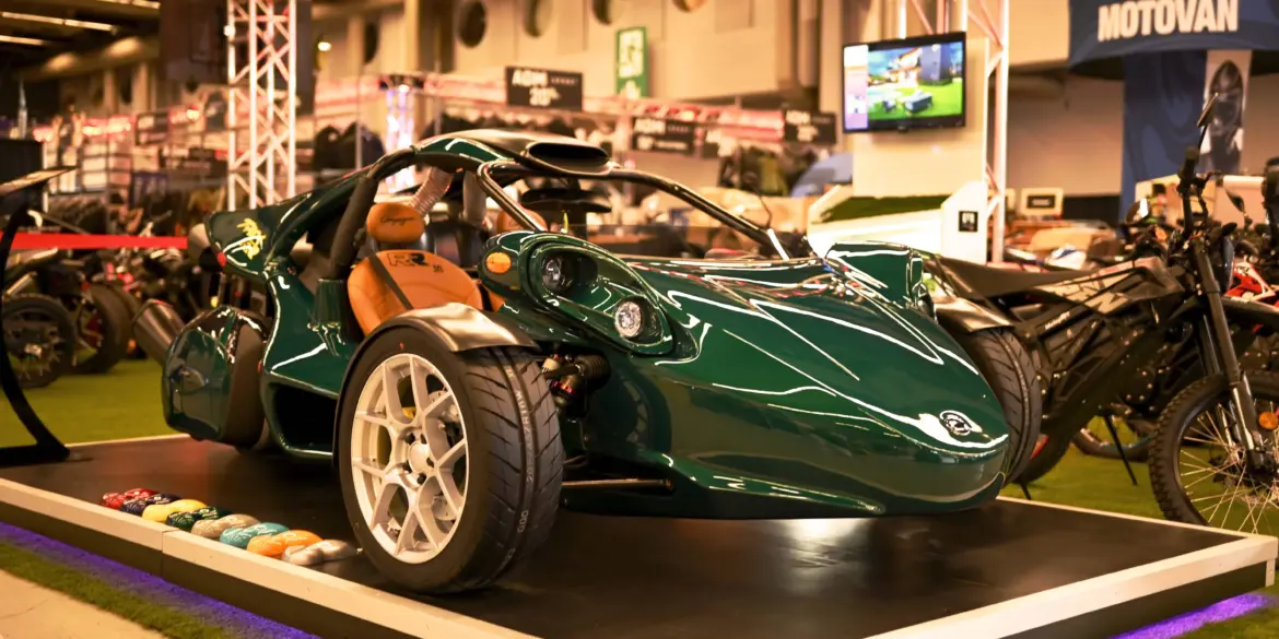 Campagna T‑Rex RR 30 Special Edition in grün mit weißen Felgen und braunen Ledersitzen auf einer Ausstellungsplattform.