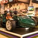 Campagna T‑Rex RR 30 Special Edition in grün mit weißen Felgen und braunen Ledersitzen auf einer Ausstellungsplattform.