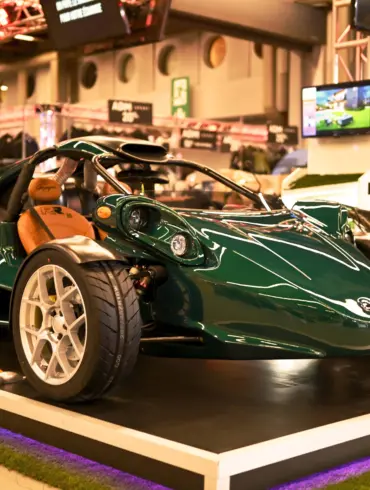 Campagna T‑Rex RR 30 Special Edition in grün mit weißen Felgen und braunen Ledersitzen auf einer Ausstellungsplattform.