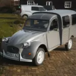 Citroën 2CV AK350 Fourgonnette von 1974 in Grau, seitlich von vorne fotografiert, auf Kopfsteinpflaster stehend.