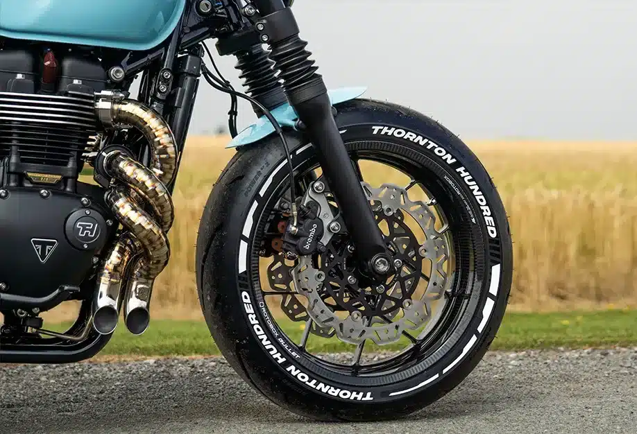 Vorderes Carbonrad mit gelochter Bremsscheibe und Twisted-Auspuff einer Thornton Hundred City Bobber