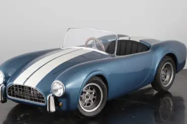 Cobra 289 Junior Kinderauto im Shelby-Blau mit weißen Rennstreifen, halbmaßstäblicher Roadster auf schwarzem Studiohintergrund.