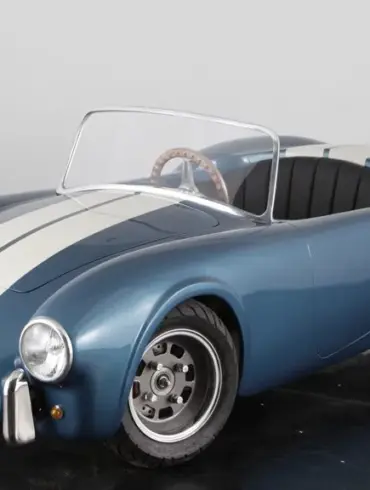 Cobra 289 Junior Kinderauto im Shelby-Blau mit weißen Rennstreifen, halbmaßstäblicher Roadster auf schwarzem Studiohintergrund.
