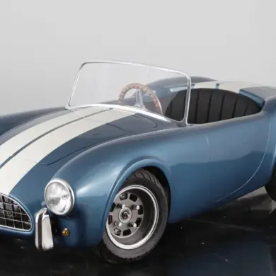Cobra 289 Junior Kinderauto im Shelby-Blau mit weißen Rennstreifen, halbmaßstäblicher Roadster auf schwarzem Studiohintergrund.