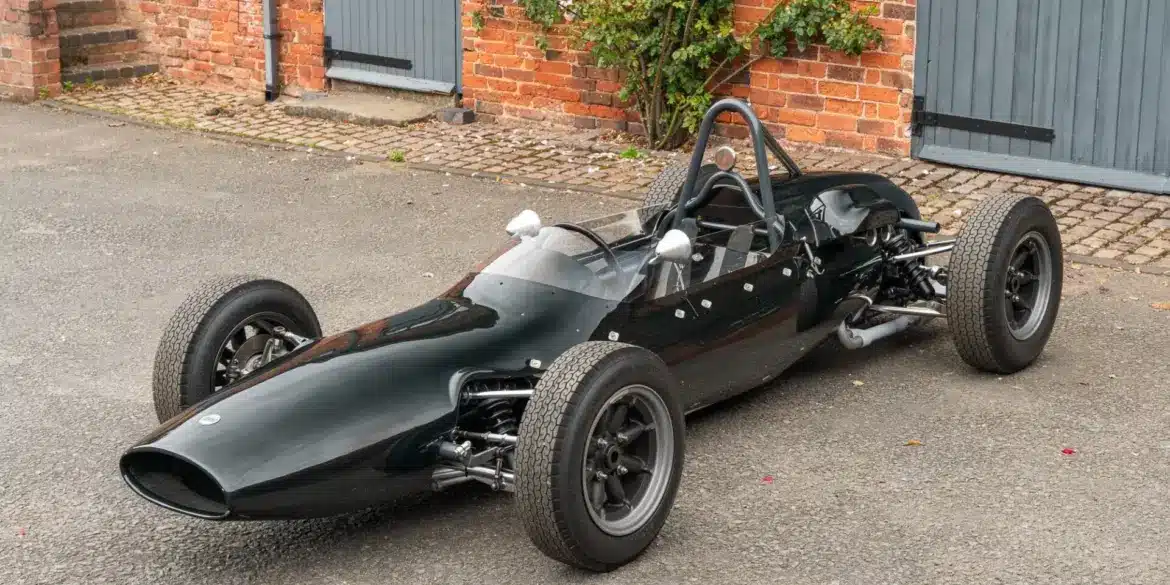 Cooper T59 Formula Junior Rennwagen von 1962 in dunkelgrüner Lackierung, frontal seitlich in einer Hofeinfahrt fotografiert.