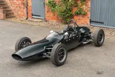 Cooper T59 Formula Junior Rennwagen von 1962 in dunkelgrüner Lackierung, frontal seitlich in einer Hofeinfahrt fotografiert.