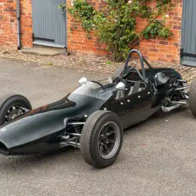 Cooper T59 Formula Junior Rennwagen von 1962 in dunkelgrüner Lackierung, frontal seitlich in einer Hofeinfahrt fotografiert.